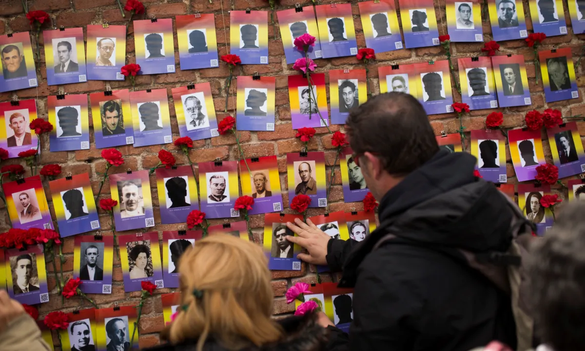 People put red carnations next to photographs during the 87th Spanish Republic anniversary ceremony to pay tribute to people killed in the Spanish Civil War at the Almudena cemetery in Madrid on April 14, 2018. (Francisco Seco/AP Photo)