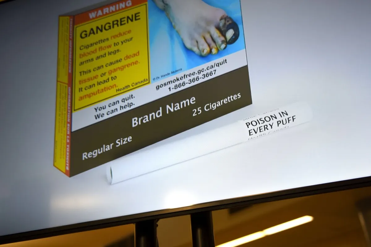 An example of cigarette packaging with expanded warnings, including a warning printed on the cigarettes themselves, is shown on a screen after a news conference, in Ottawa, on June 10, 2022. (The Canadian Press/Justin Tang)