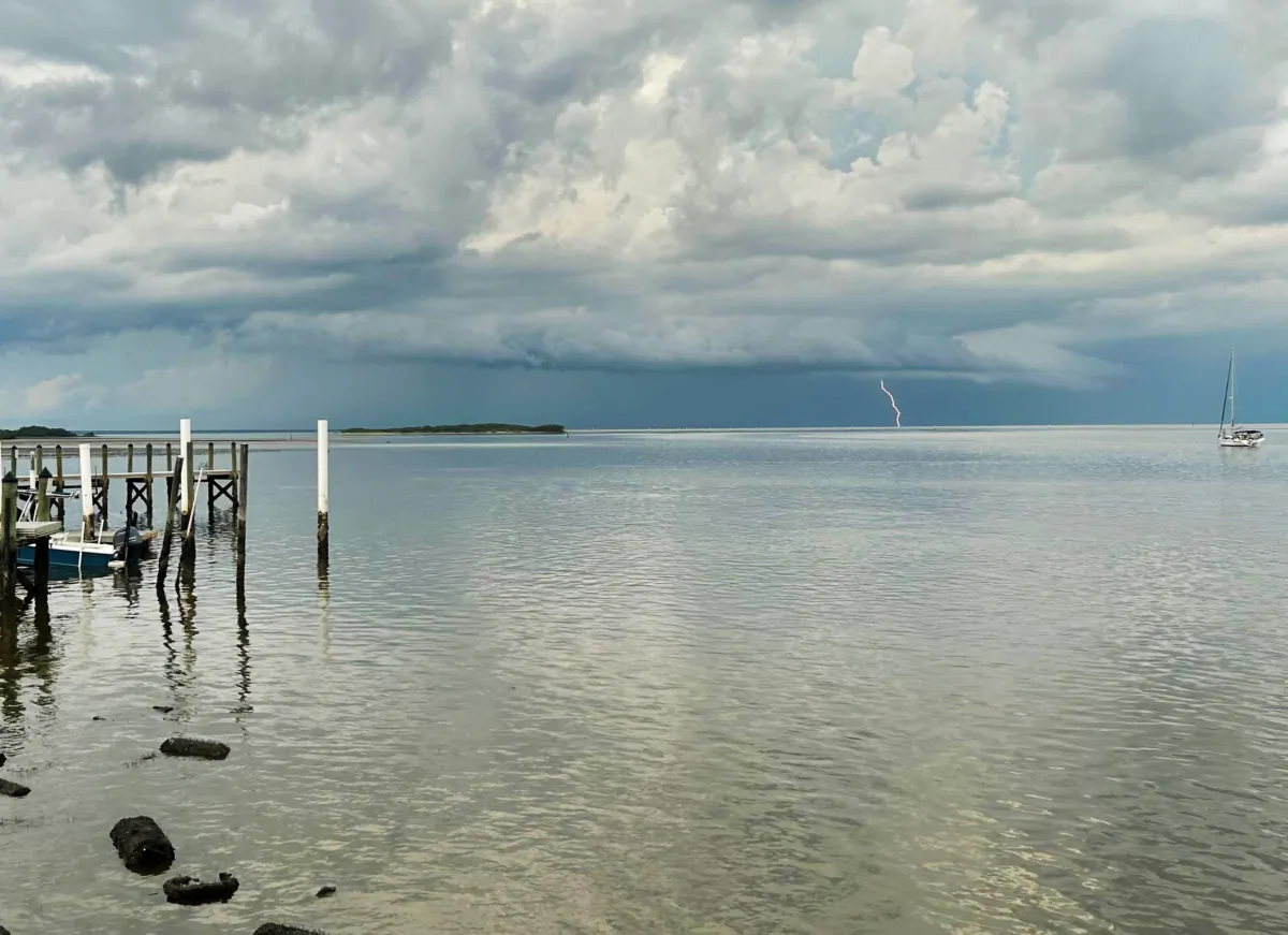 Lightning strikes in the distance as boaters head in to docks to escape a storm bearing down on Cedar Key, Fla. on July 31, 2023. (Natasha Holt for The Epoch Times)