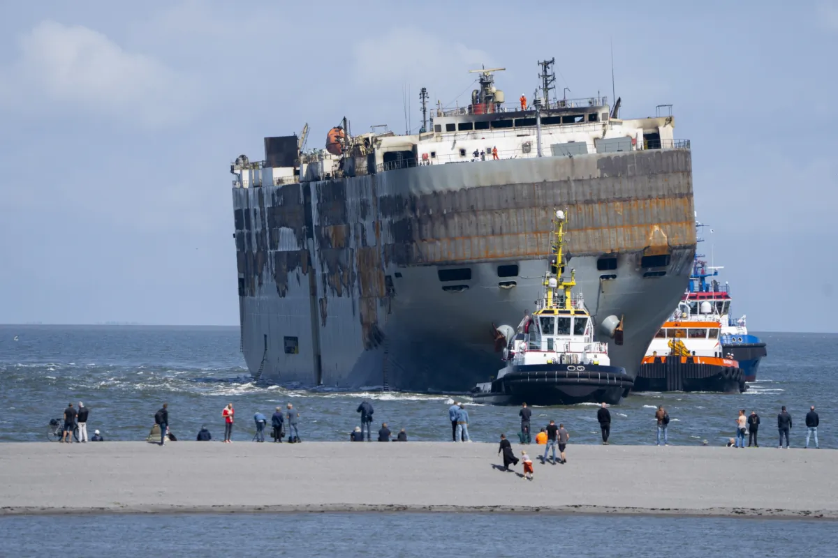 Stricken cargo ship Fremantle Highway, that caught fire while transporting thousands of cars, including nearly 500 electric vehicles, from Germany to Singapore, is towed into the port of Eemshaven, the Netherlands, on Aug. 3, 2023. (Peter Dejong/AP Photo)