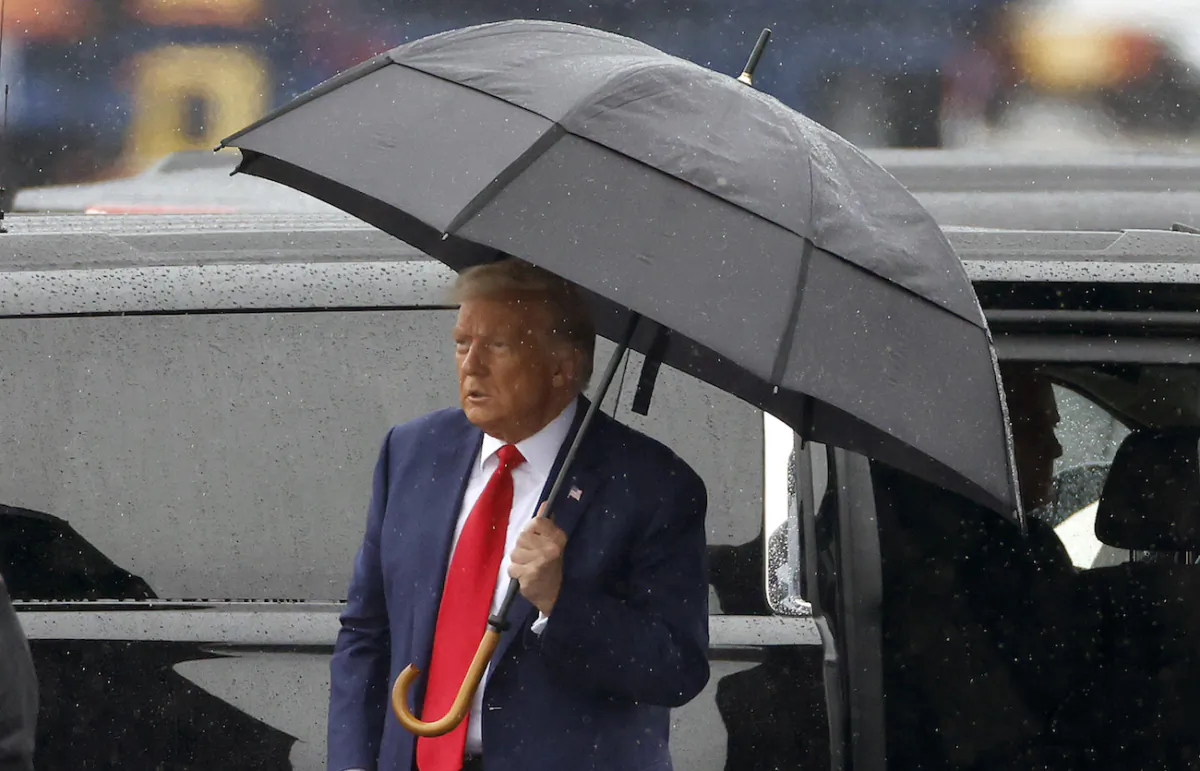 Former U.S. President Donald Trump holds an umbrella as he arrives at Reagan National Airport following an arraignment in a Washington court in Arlington, Va., on Aug. 3, 2023. (Tasos Katopodis/Getty Images)