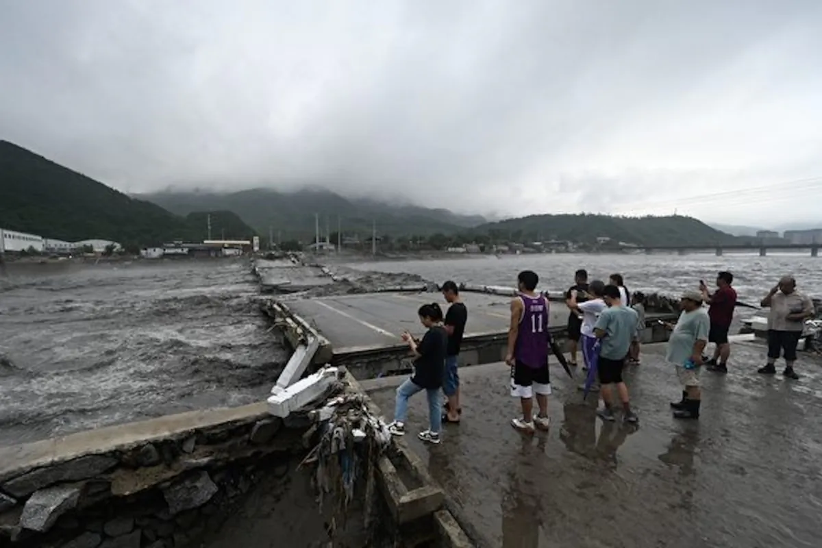 People watch a collapsed bridge on the Dashihe River after heavy rains in Fangshan district in Beijing on Aug. 1, 2023. (Pedro Pardo/AFP via Getty Images)