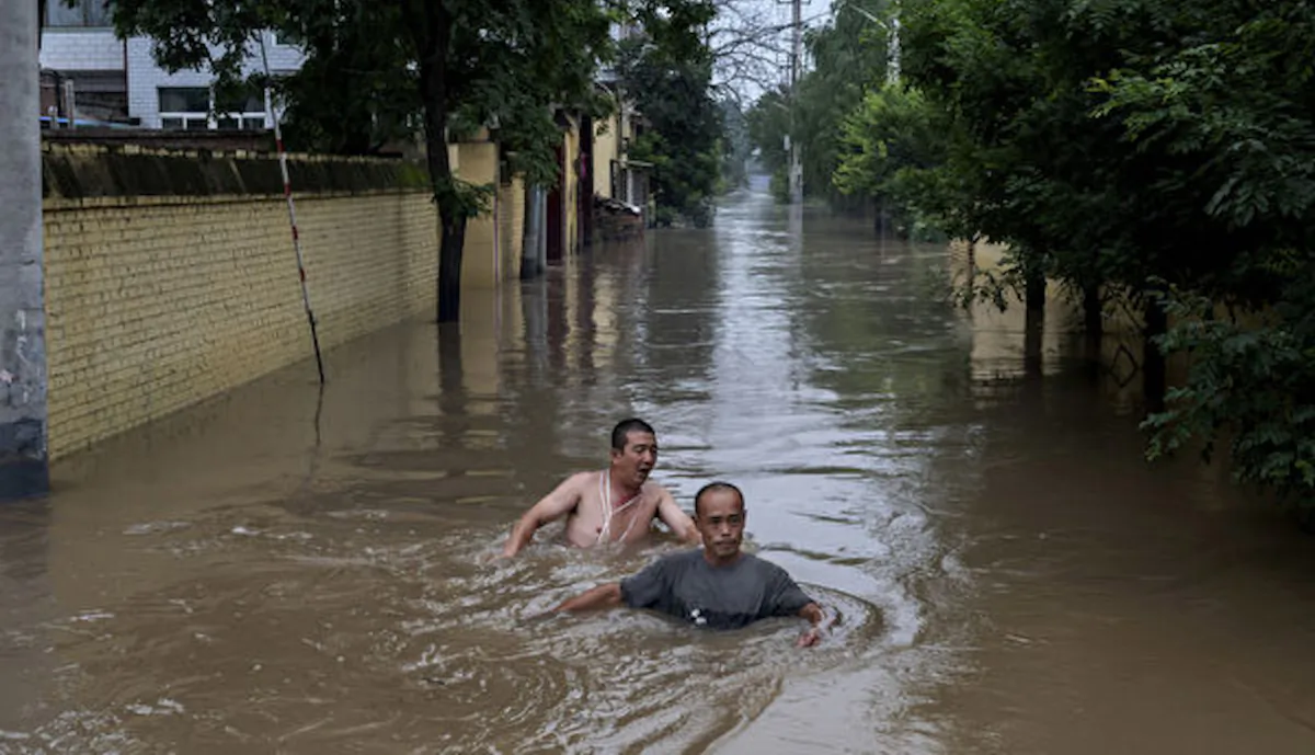 Local residents struggle in deep fast moving water as they make their way toward rescuers in a boat in an area inundated with floodwaters near Zhuozhou, Hebei Province, south of Beijing, on Aug. 3, 2023. (Kevin Frayer/Getty Images)