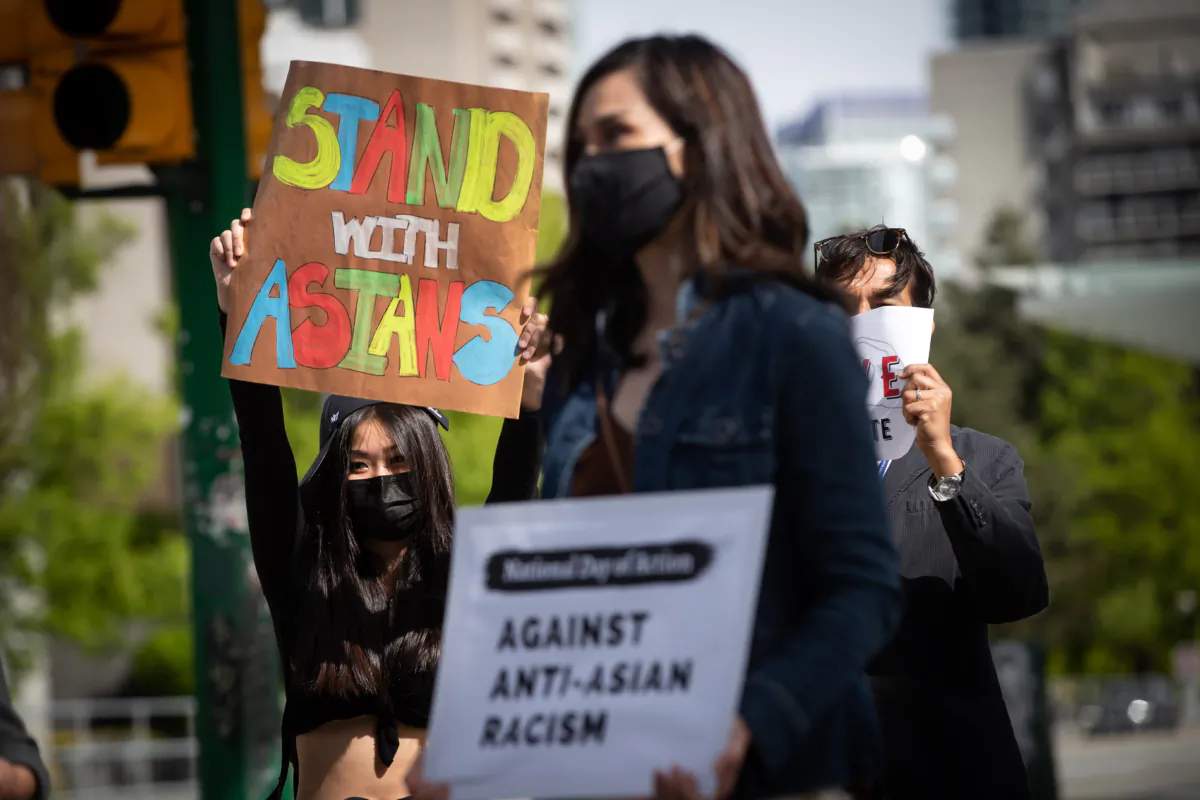 People hold signs during a rally against anti-Asian racism in Burnaby, B.C., on May 10, 2021. (Darryl Dyck/The Canadina Press)