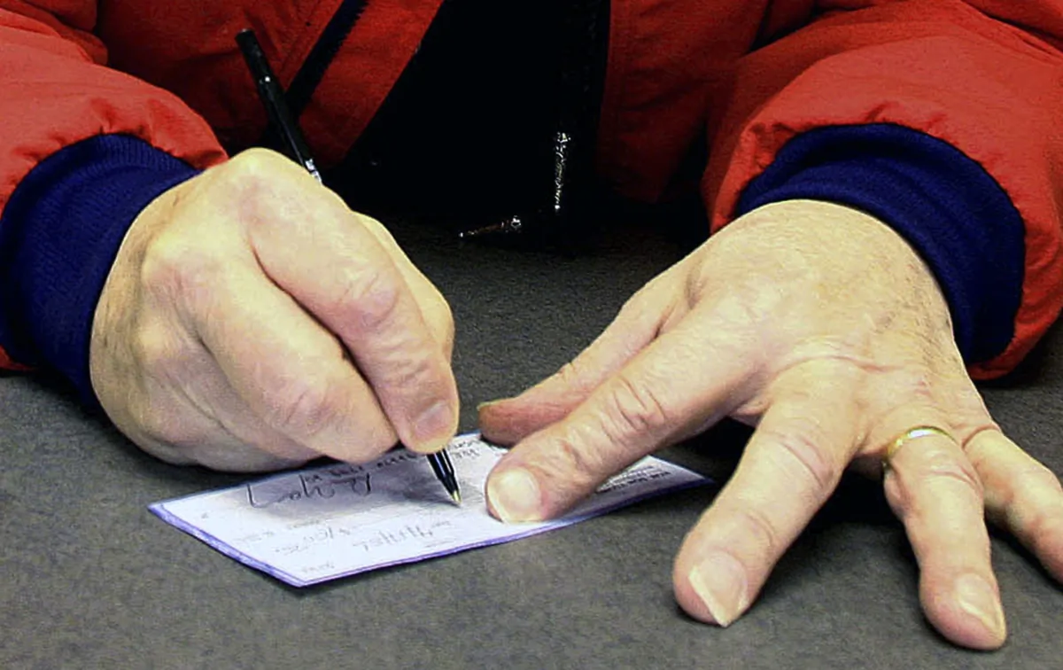 A man signs a check in Anchorage, Alaska, on April 17, 2006. (Al Grillo/AP)