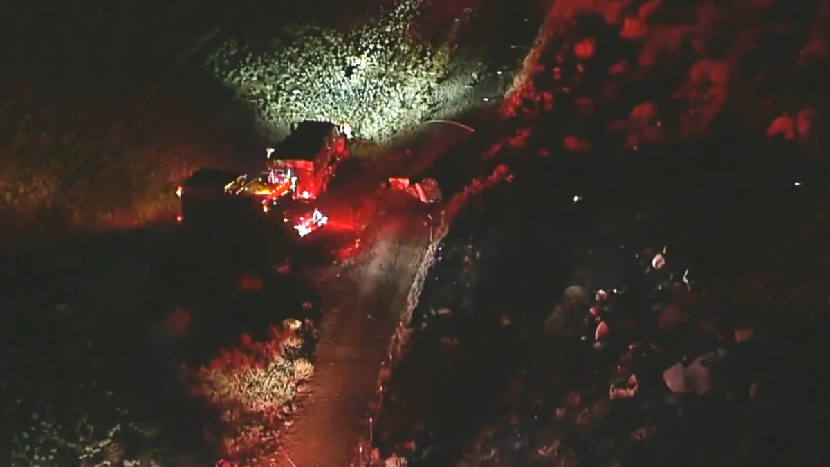 This aerial image taken from video provided by ABC7 Los Angeles shows the scene of a firefighting helicopter crash, with emergency vehicles at the base of a mountain and the area blocked off with police tape, in Cabazon, Calif., on Aug. 6, 2023. (ABC7 Los Angeles via AP)