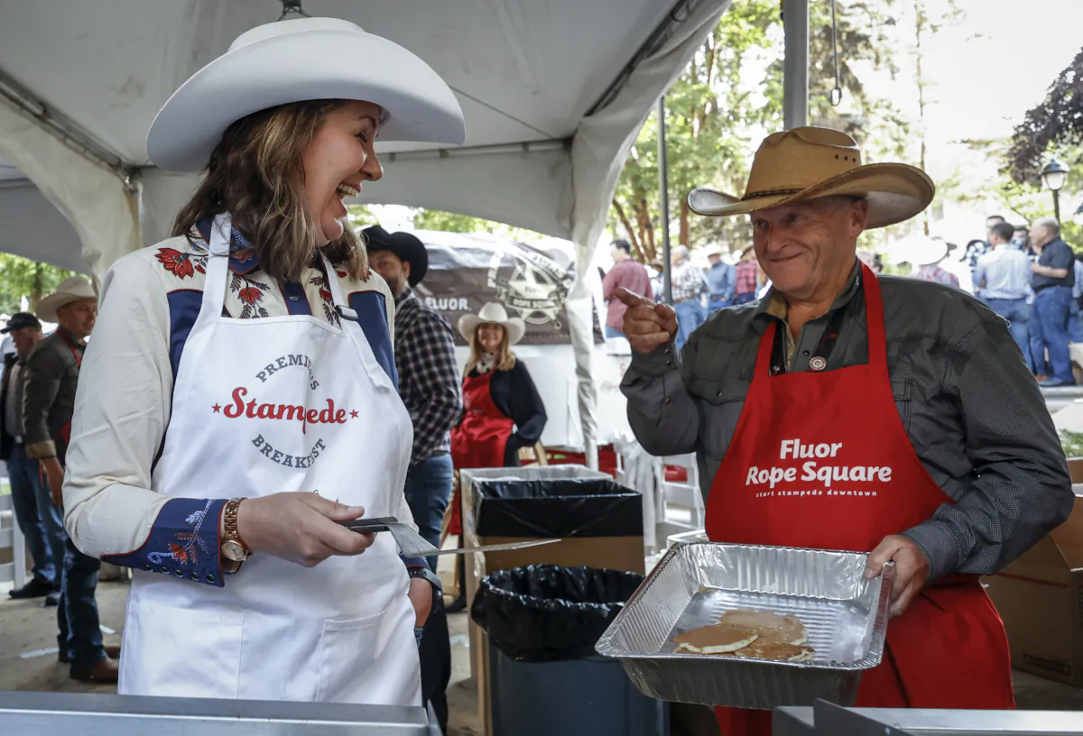 Alberta Premier Danielle Smith tosses pancakes over her shoulder at her Stampede pancake breakfast  in Calgary, on July 10, 2023. (The Canadian Press/Jeff McIntosh)