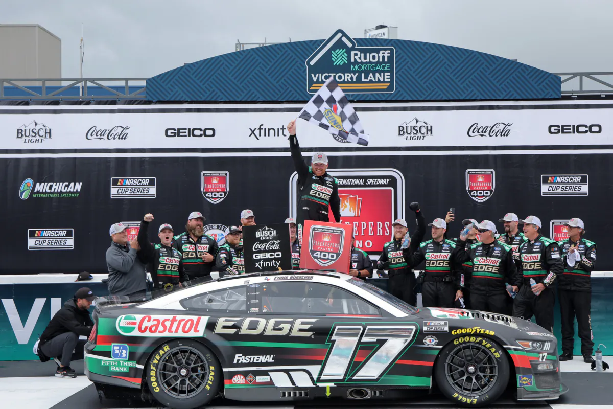Chris Buescher, driver of the (17) Castrol Edge Ford, waves the checkered flag in victory lane after winning the NASCAR Cup Series FireKeepers Casino 400 at Michigan International Speedway in Brooklyn, Michigan, on Aug. 7, 2023. (Jonathan Bachman/Getty Images)