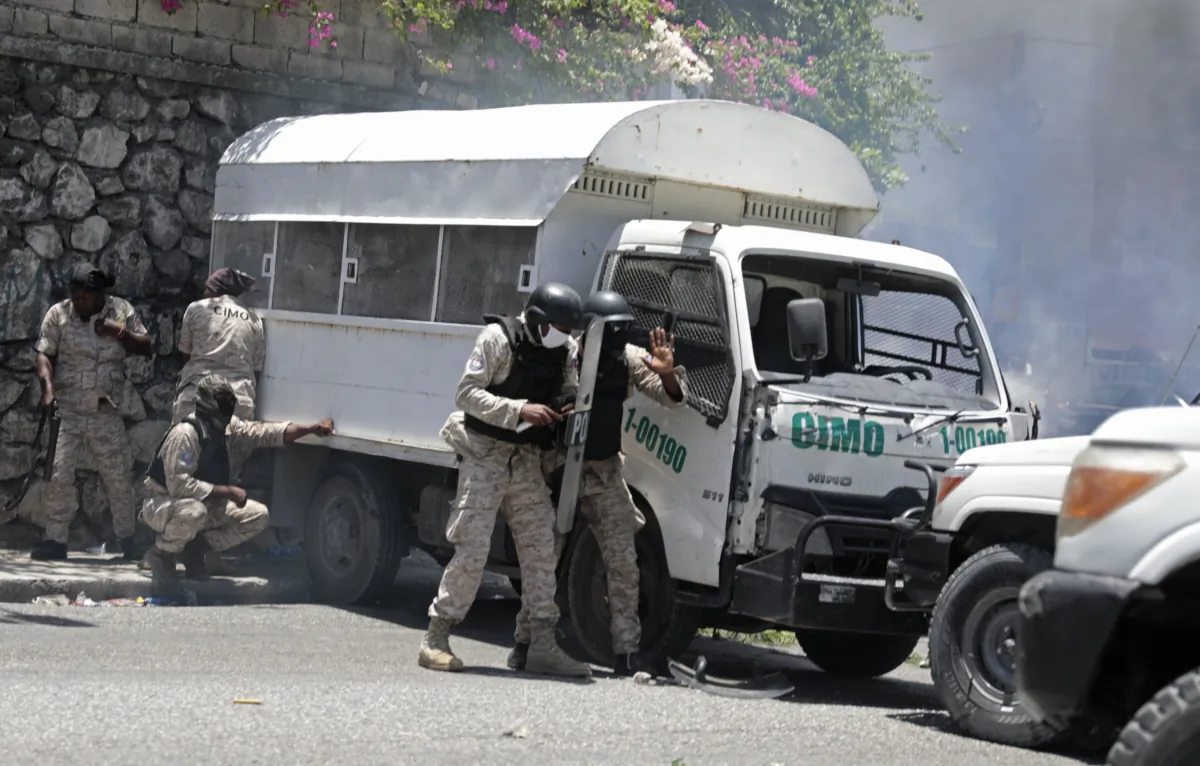 Police take cover from rocks thrown by demonstrators in Port-au-Prince, Haiti, on Aug. 7, 2023. (Odelyn Joseph/AP Photo)