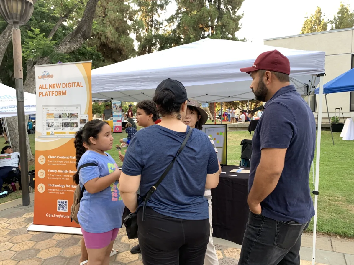 Local residents talking to a Gan Jing World's representative at a National Night Out event at Pomona Civic Center in Pomona, Calif., on Aug. 1, 2023. (Linda Jiang/The Epoch Times)