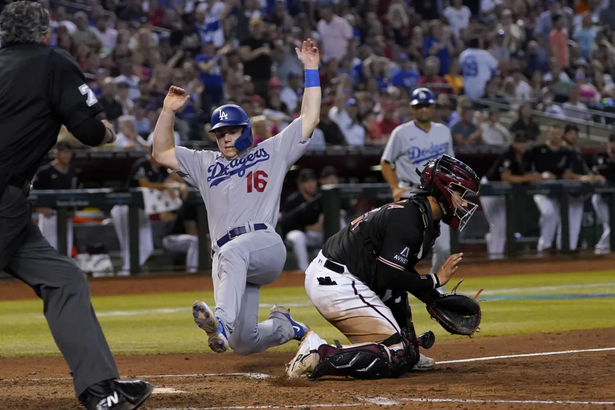 Los Angeles Dodgers' Will Smith scores on a two-run single by David Peralta, next to Arizona Diamondbacks catcher Jose Herrera during the eighth inning of a baseball game in Phoenix on Aug. 9, 2023. (Matt York/AP Photo)