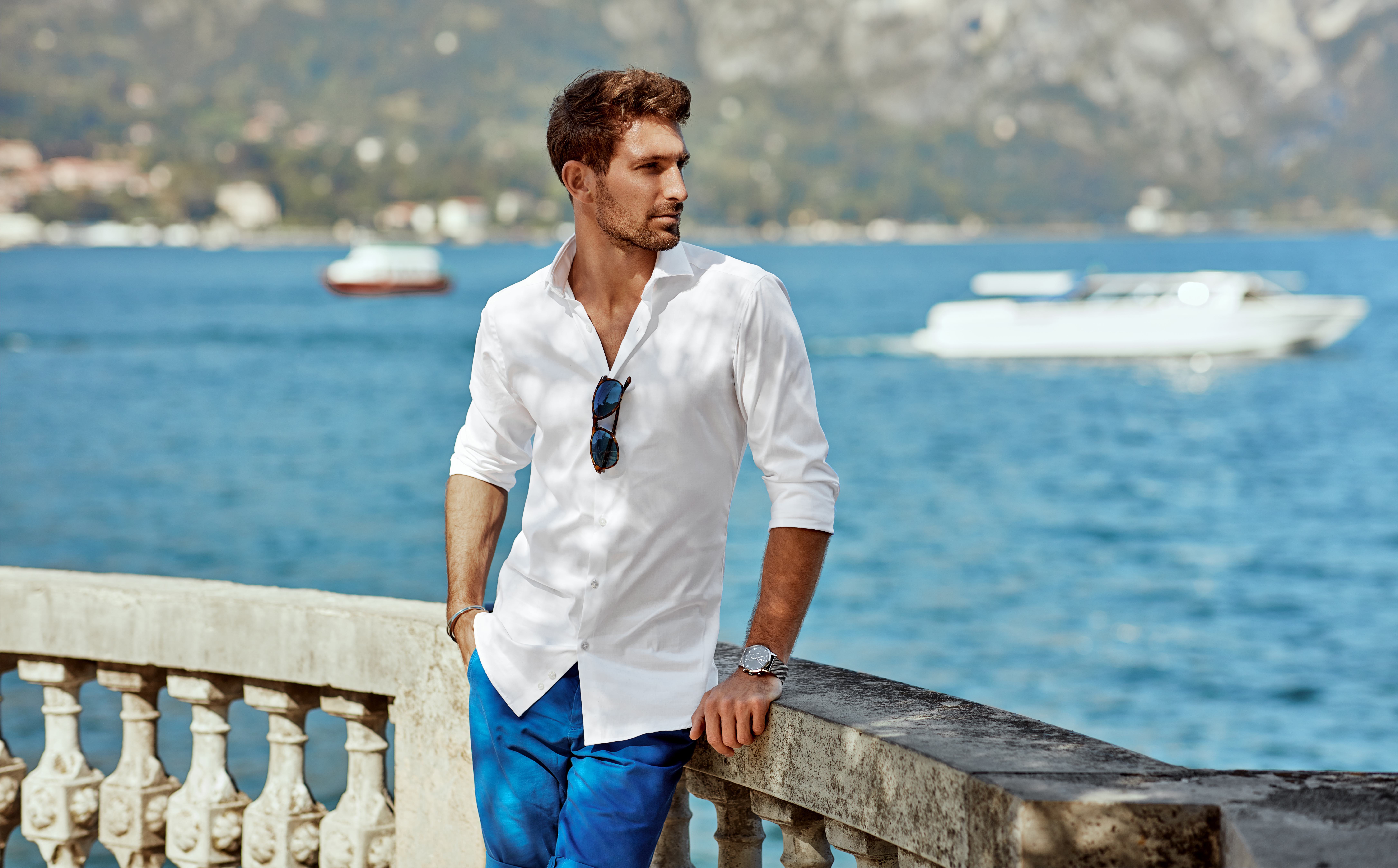 Man wearing elegant white shirt and posing outdoor near the river in alps