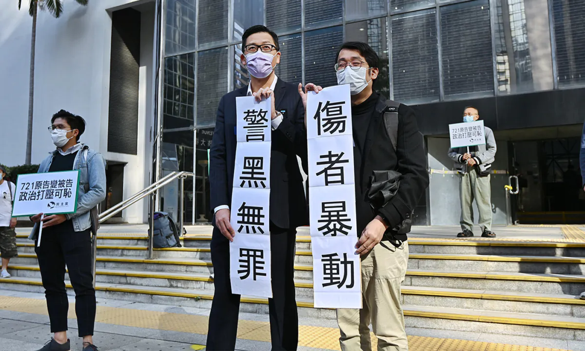 Lam Cheuk-ting stands outside the court with Democratic Party members, holding signs that read "From Plaintiff to Defendant" and "Gangster Police Free from Crime, Innocence Shattered," on Jan. 5 2021. (Sung Pi-Lung/The Epoch Times)
