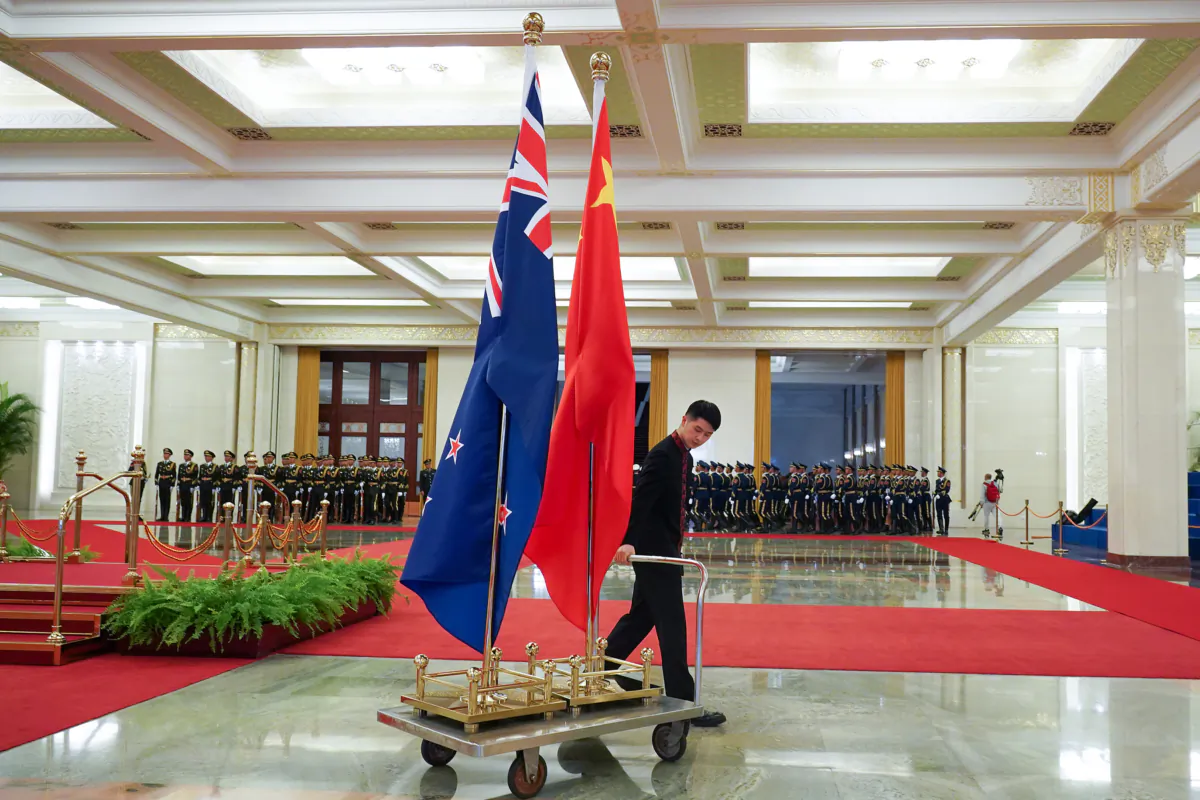 An attendant takes away the national flags at the end of the meeting between Chinese Premier Li Keqiang and New Zealand Prime Minister Jacinda Ardern at the Great Hall of the People in Beijing on April 1, 2019. (Andrea Verdelli/Getty Images)
