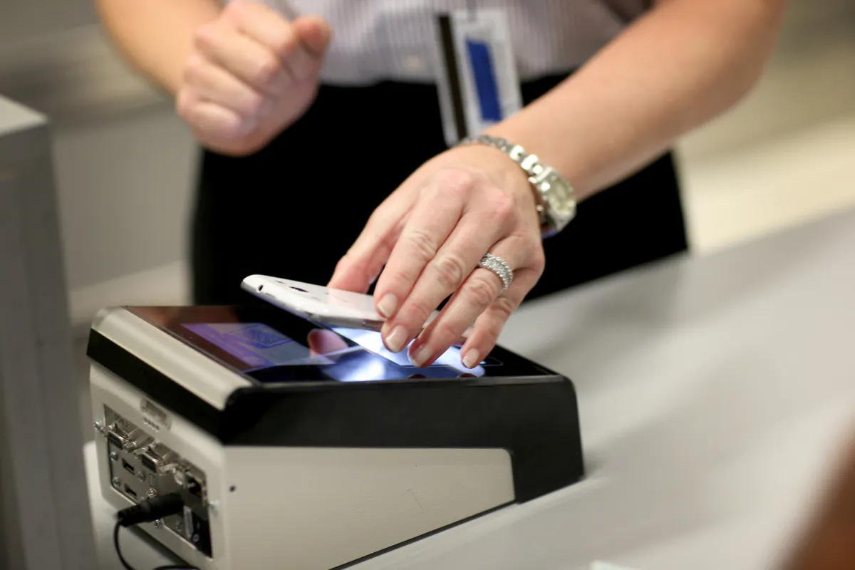 Christine Rolin passes her iphone over a scanner as she uses a mobile app for expedited passport and customer screening for international travelers arriving at Miami International Airport on March 4, 2015 in Miami, Florida. (Joe Raedle/Getty Images)