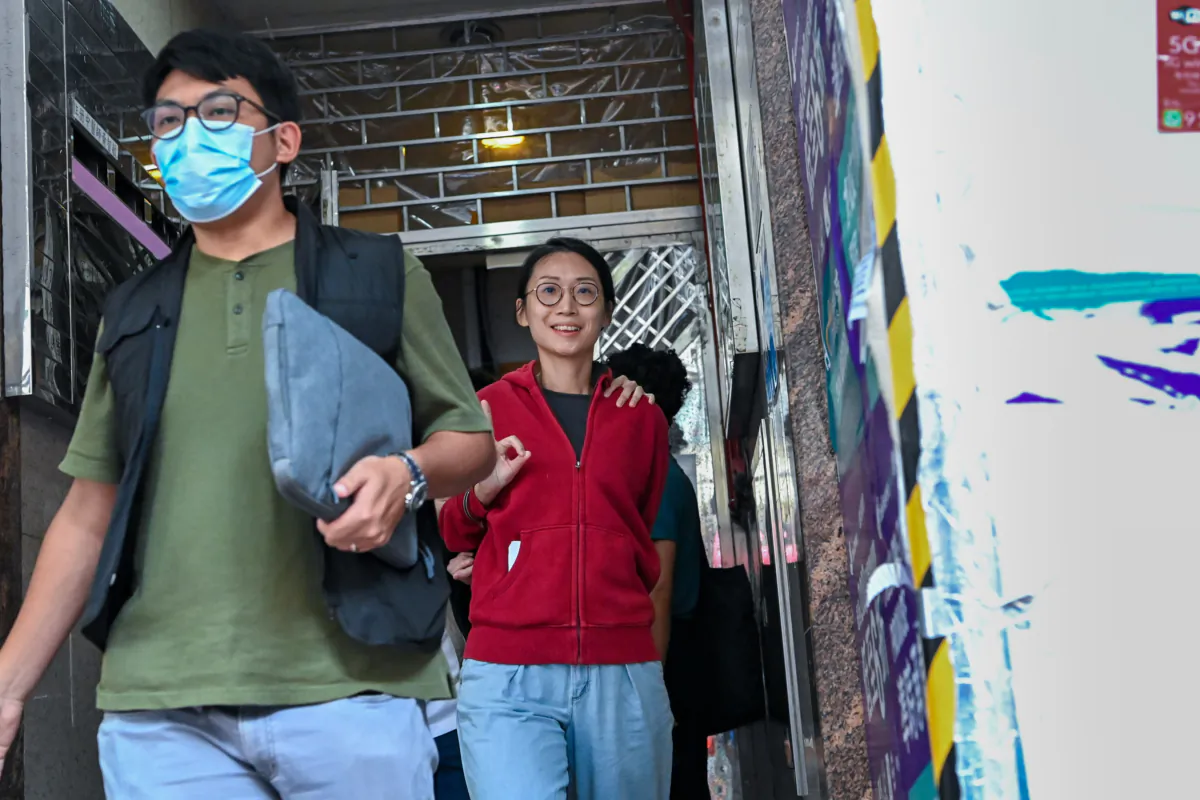Ms. Bobo Yip Po-lam, who was being escorted by the police, smiled at the camera and held up an "OK" sign to the media, in Hong Kong, on August 10, 2023. (Sung Pi-lung/The Epoch Times)