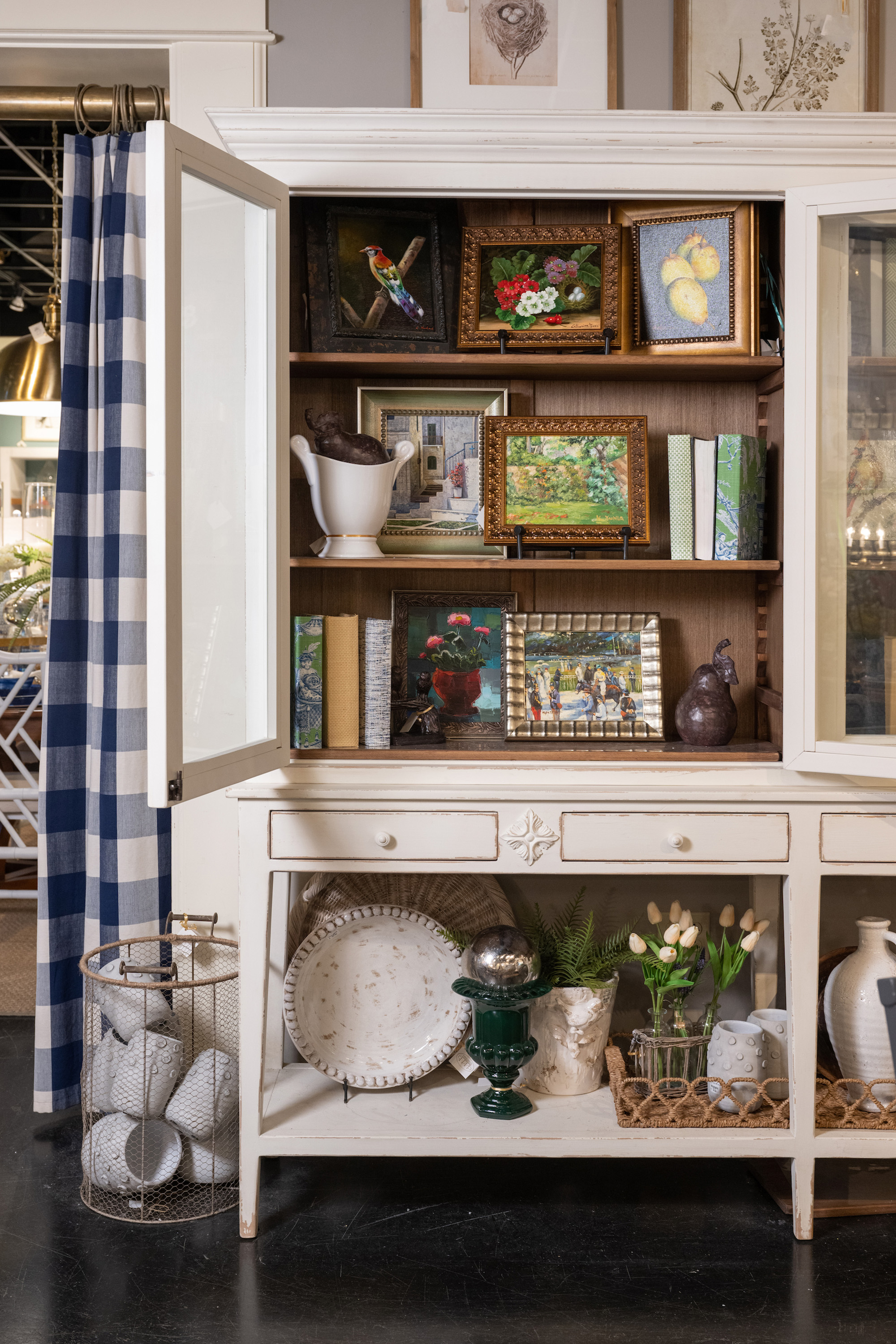 A peek into this curio cabinet reveals a collection of oil paintings and books.