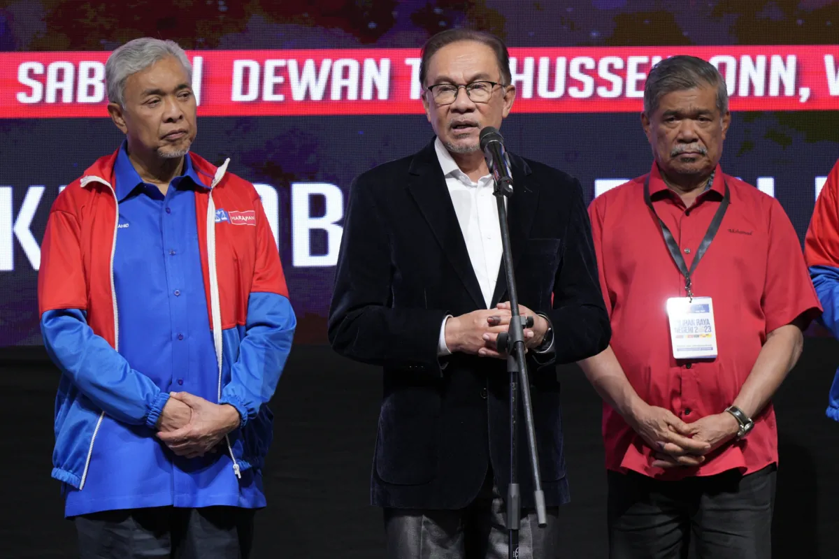 Malaysian Prime Minister Anwar Ibrahim, centre, speaks to media as deputy prime minister Ahmad Zahid Hamidi, left, standing with other leaders after announcing the result of state election at UMNO headquarters in Kuala Lumpur, Malaysia, on Aug. 12, 2023. (Vincent Thian/AP Photo)