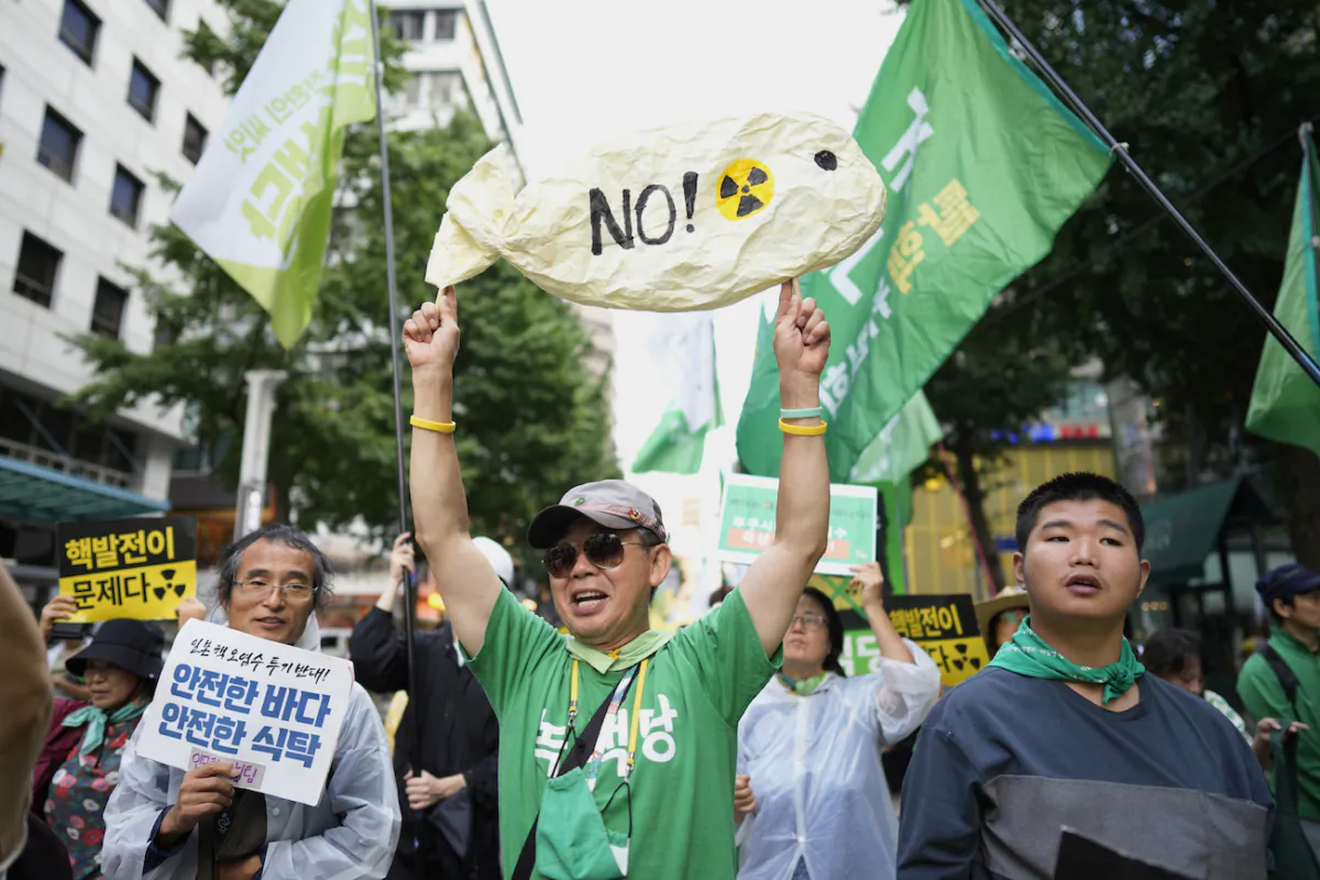 People hold banners and posters to protest Japan's plan to release treated radioactive water from the wrecked Fukushima nuclear power plant, during a match along a street in Seoul, South Korea, on Aug. 12, 2023. (AP Photo/Lee Jin-man)