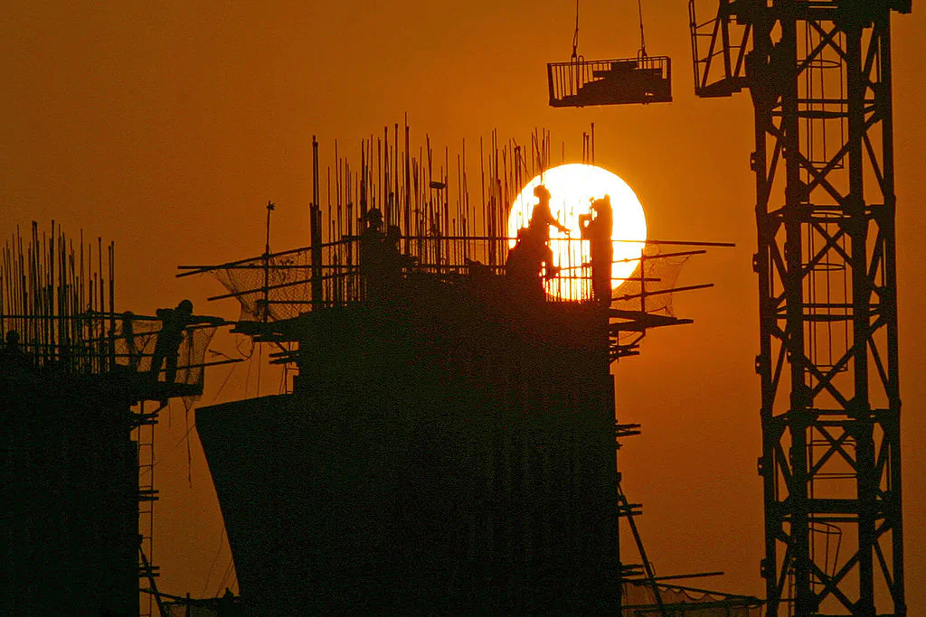 Chinese laborers work at a construction site at sunset in Chongqing, China, on Mar. 6, 2005. (China Photos/Getty Images)
