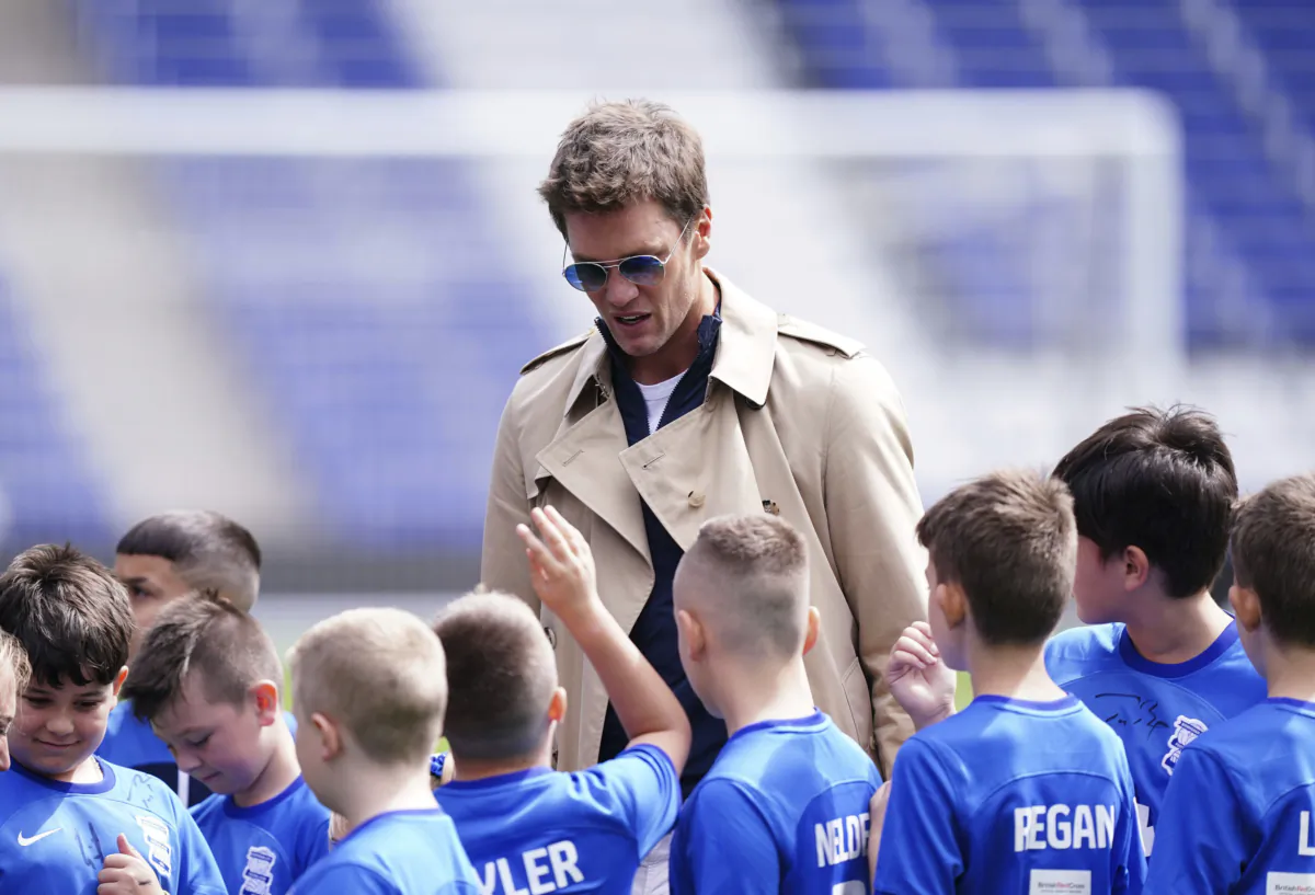 Birmingham City co-owner Tom Brady signs autographs for young fans before the Championship soccer match between Birmingham City and Leeds United at St. Andrew's in Birmingham, England, on Aug. 12, 2023. (Mike Egerton/PA via AP)