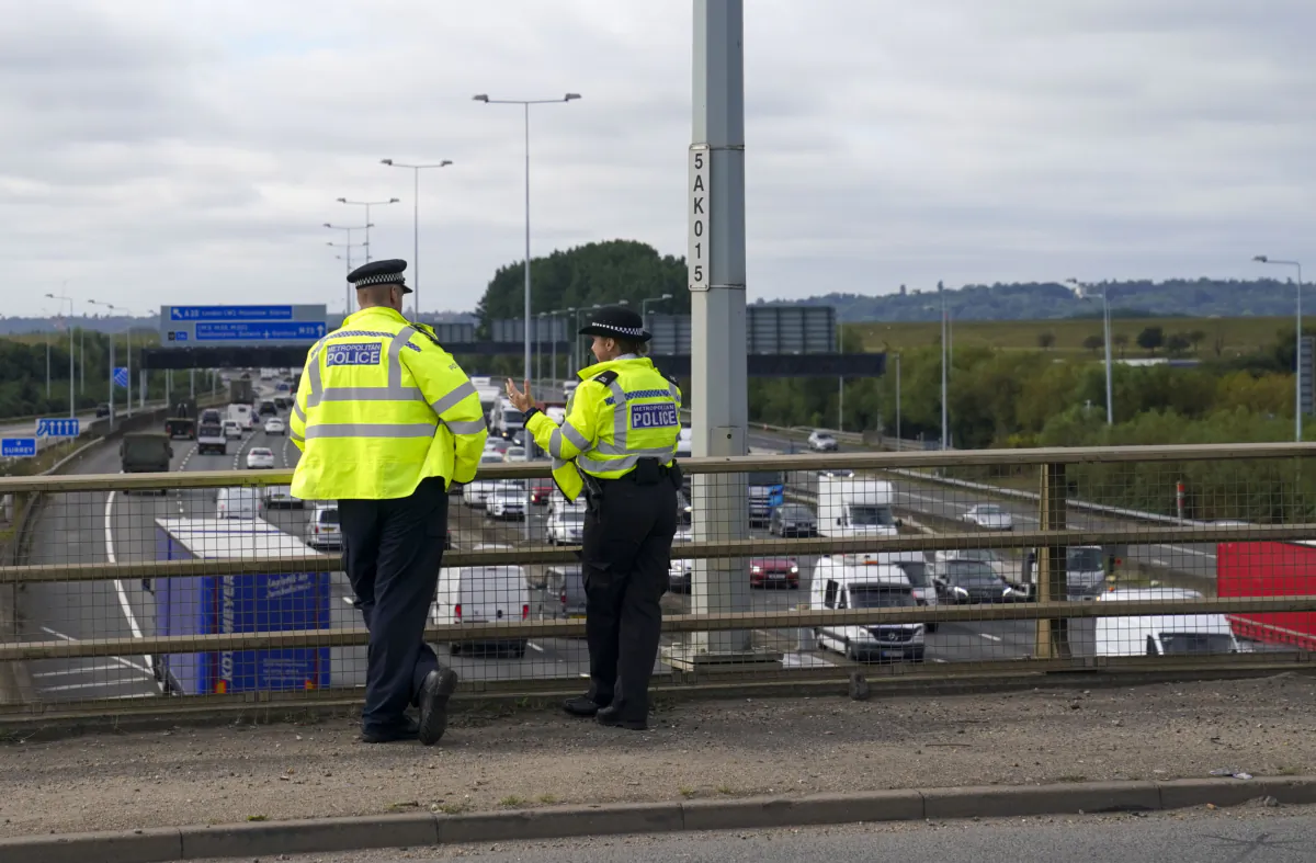 Police officers watch traffic on the M25 motorway near Heathrow Airport outside London, on Sep. 23, 2021. (Steve Parsons/PA)