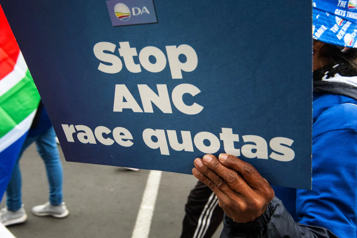 A person holds a placard as supporters of the Democratic Alliance, South Africa's main opposition party, marches through the city streets to protest against the ruling African National Congress new proposal for employment quotas along racial lines, in Cape Town on July 26, 2023. (Rodger Bosch/ AFP via Getty Images)