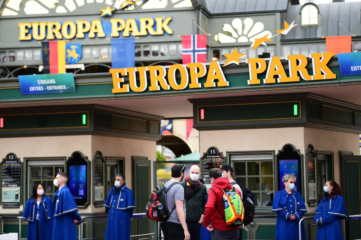 Visitors are watched by staff members as they wait to enter the main entrance of Europa-Park in Rust, western Germany, on May 21, 2021. (Sebastien Bozon/AFP via Getty Images)