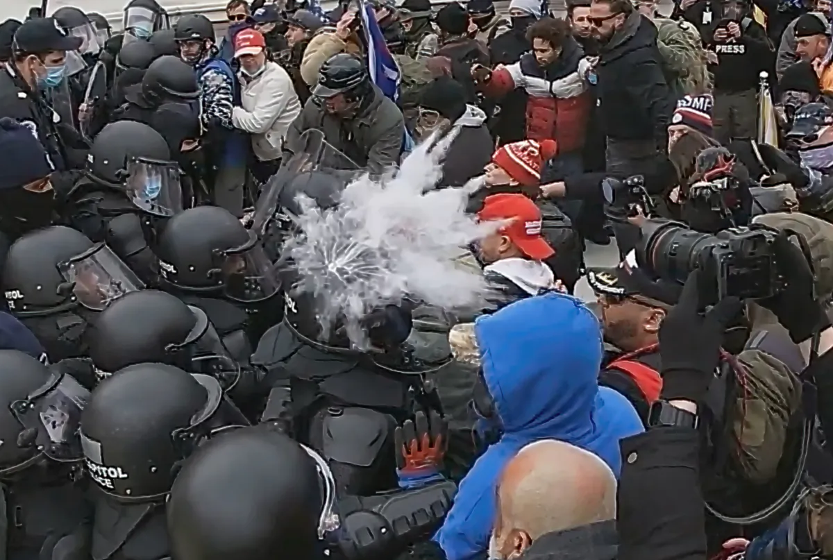A U.S. Capitol Police officer is struck in the helmet by a pepper ball fired from above by a fellow officer on the Capitol's west plaza in Washington on Jan. 6, 2021. (Special to The Epoch Times)