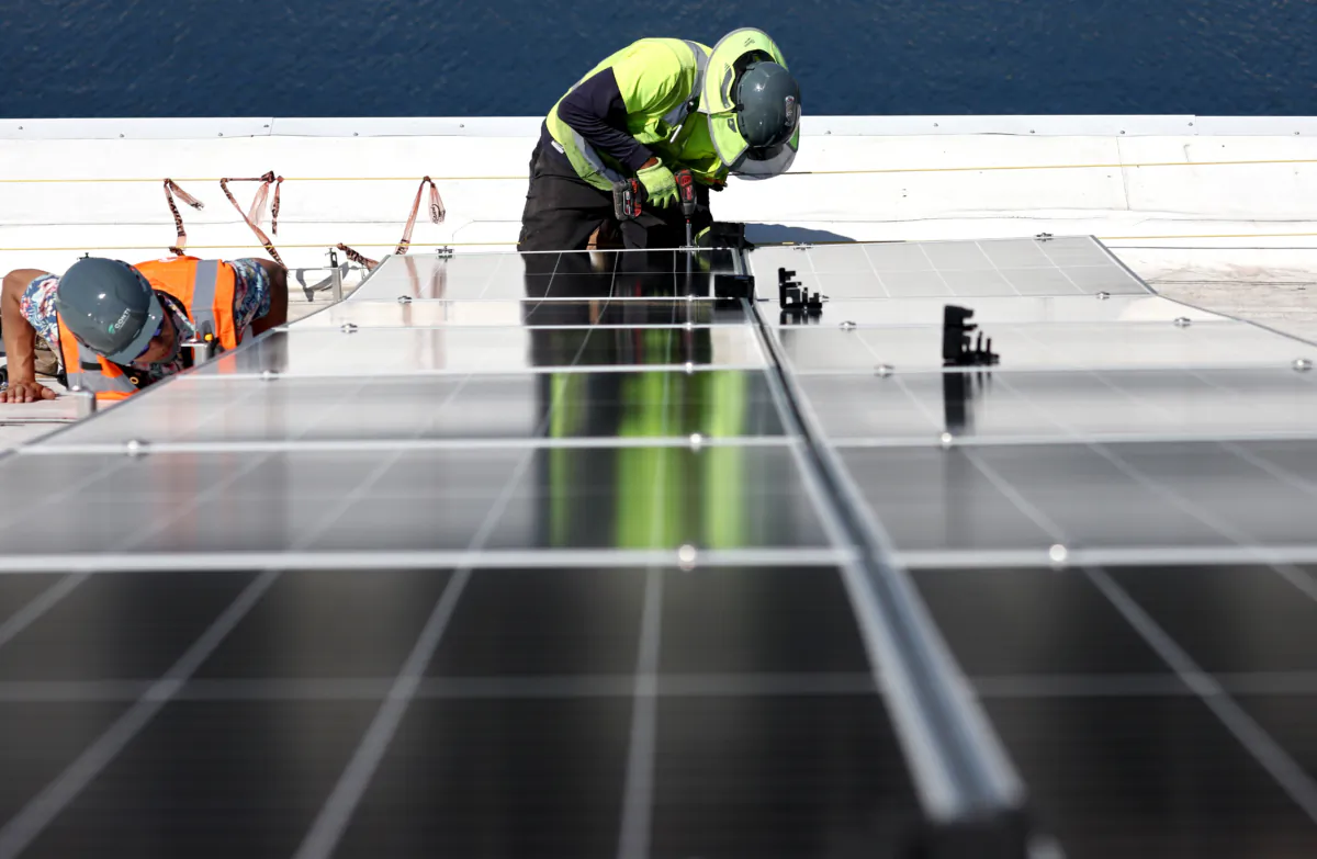 Workers install solar panels during the completion phase of a 4-acre solar rooftop atop AltaSea's research and development facility at the Port of Los Angeles in Los Angeles, Calif., on April 21, 2023. (Mario Tama/Getty Images)
