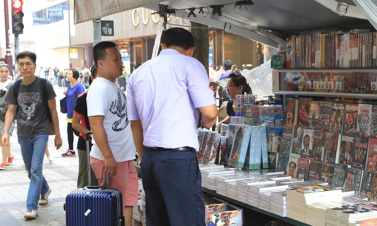 Two mainland tourists purchase banned books at a newsstand in Tsim Sha Tsui, Hong Kong, on July 30, 2014. (Adrian Yu/The Epoch Times)