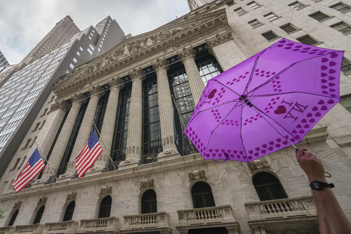 An umbrella held by a tour group leader passes the front of the New York Stock Exchange in New York on Aug. 16, 2023. (J. David Ake/AP Photo)