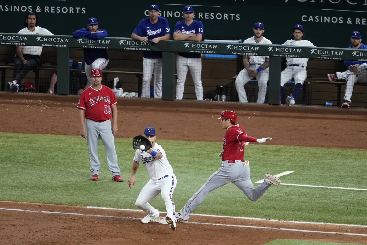 Texas Rangers first baseman Nathaniel Lowe waits for the throw as Los Angeles Angels' Shohei Ohtani reaches for a single during the third inning of a baseball game in Arlington, Texas, Aug. 16, 2023. (Tony Gutierrez/AP Photo)