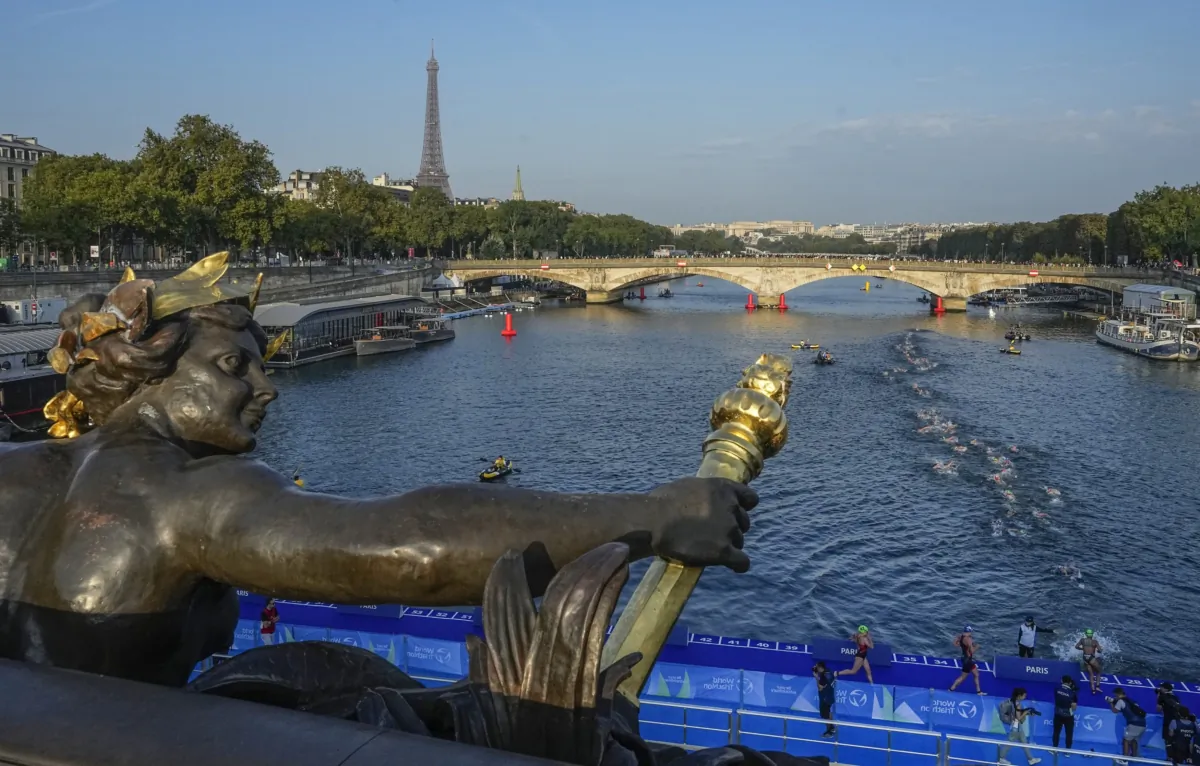 Athletes dive and swim in the Seine river from the Alexander III bridge on the first leg of the women's triathlon test event for the Paris 2024 Olympics Games in Paris on Aug. 17, 2023. (Michel Euler/AP Photo)