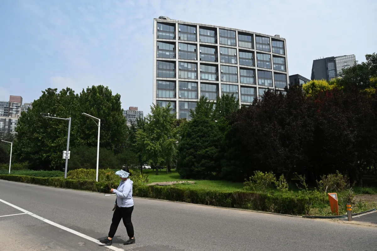 A woman walks on a street in front of the Beijing office of Zhongrong International Trust Co., partly owned by Zhongzhi Enterprise Group, in Beijing on Aug. 17, 2023. (Greg Baker/AFP via Getty Images)