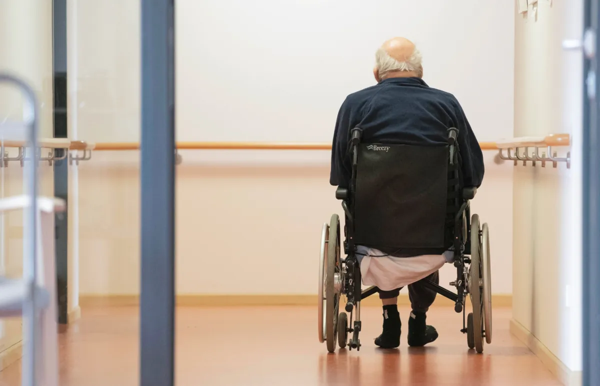 A resident in the wheelchair makes his way on a floor in a senior living facility. (Thomas Kienzle/AFP via Getty Images)