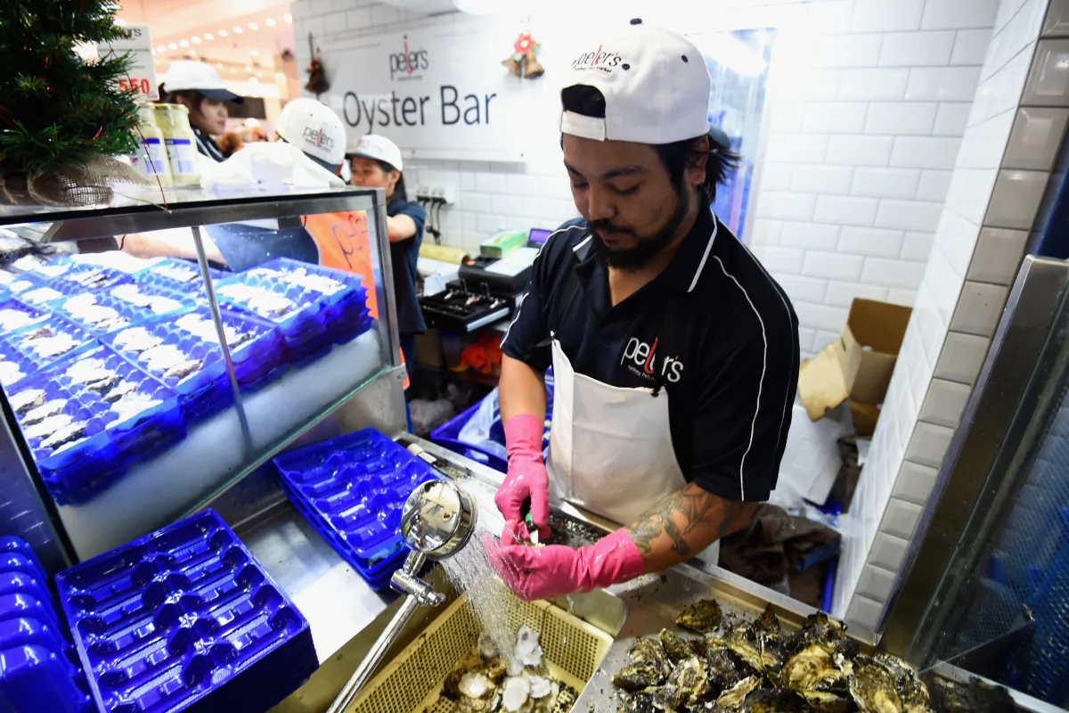 A fishmonger shucks an oyster at the Sydney Fish Market in Sydney, Australia, on on Dec. 24, 2015. (Cameron Spencer/Getty Images)