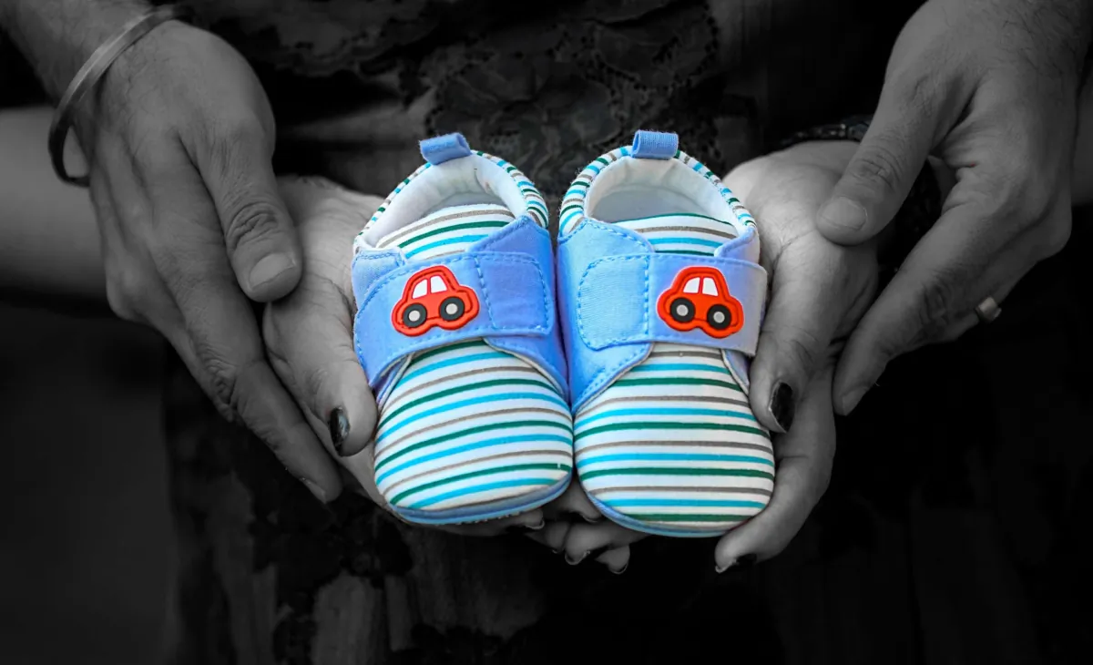 Undated photo showing two pair of hands holding a pair of baby shoes. (PA)