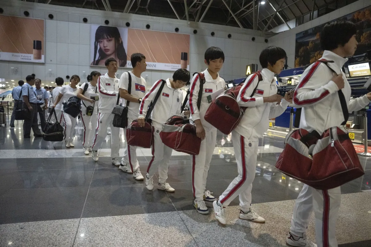 North Korean women wearing track suits with the North Korean flag and the words Taekwon-Do printed on the back walk to Chinese customs after checking in for a flight to Astana at the Capital Airport in Beijing on Aug. 18, 2023. (Ng Han Guan/AP Photo)