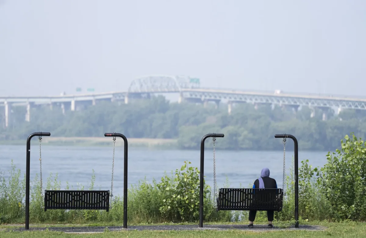 A woman looks out at the St. Lawrence River in LaSalle, Que., on June 30, 2023. (The Canadian Press/Christinne Muschi)