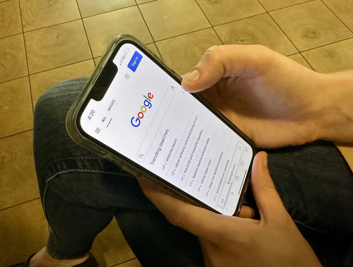 A teen holds a smartphone and prepares to do a search on Google, where trending search terms are showing, in Sarasota, Fla., on Aug. 18, 2023. (Nanette Holt/The Epoch Times)