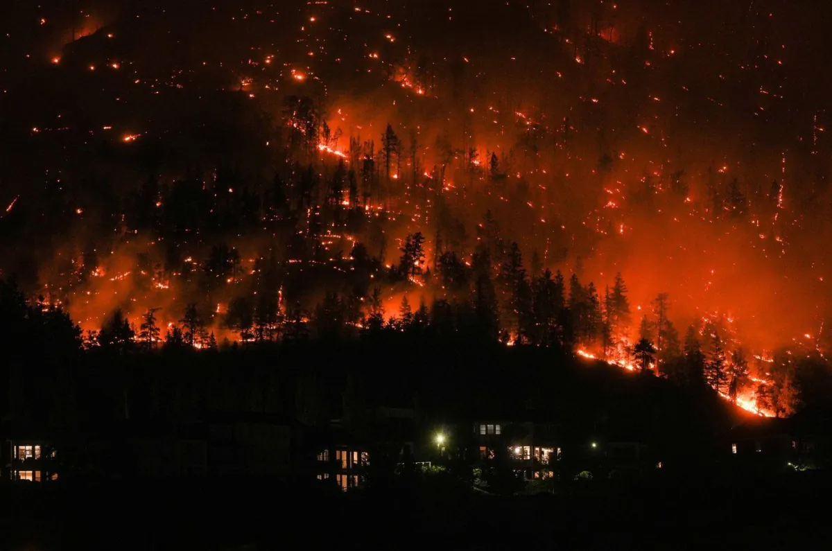 The McDougall Creek wildfire burns on the mountainside above houses in West Kelowna, B.C., on Aug. 18, 2023. (The Canadian Press/Darryl Dyck)