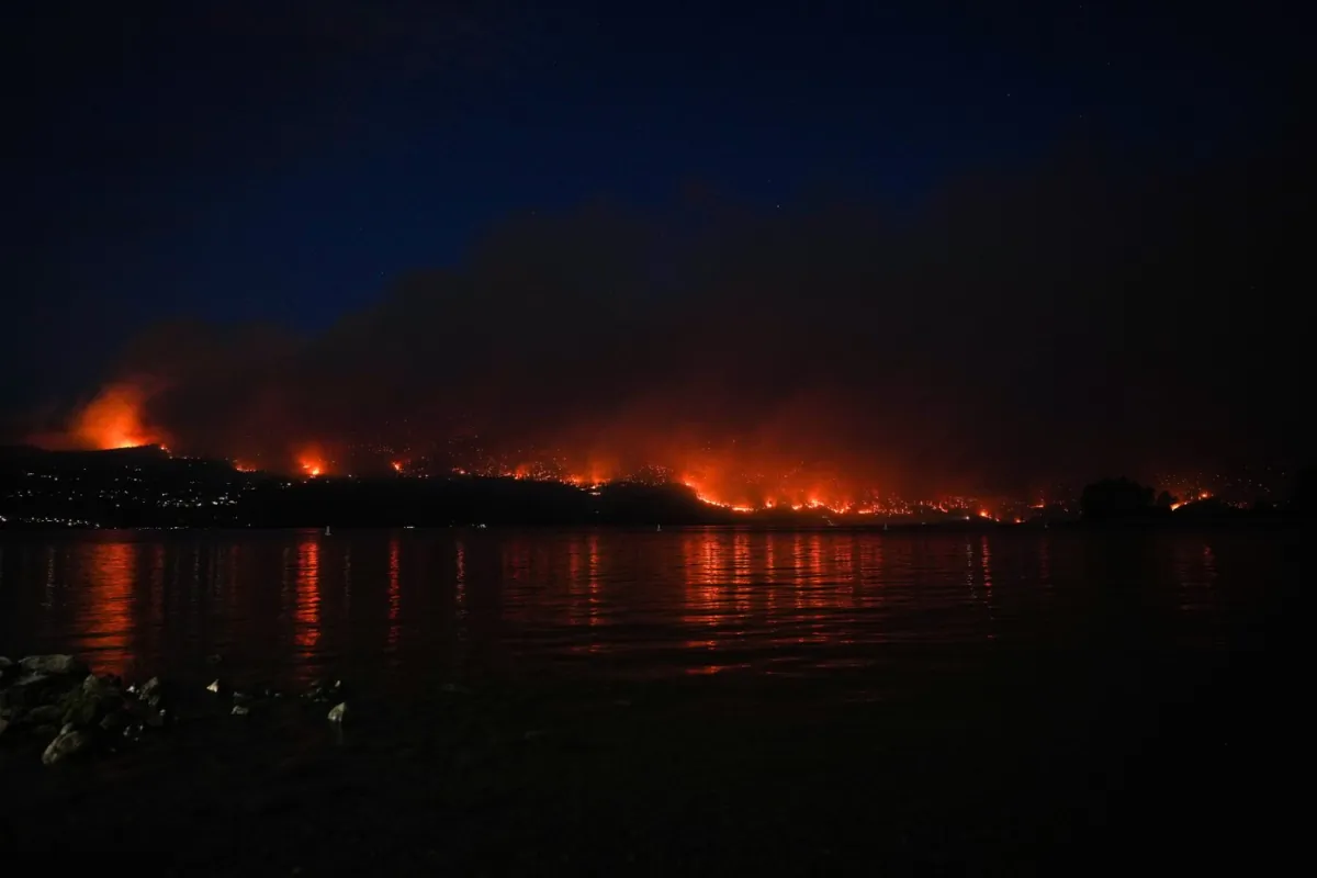 The McDougall Creek wildfire burns on the mountainside above lakefront homes in West Kelowna, B.C., on Aug. 18, 2023. (Darryl Dyck/The Canadian Press)