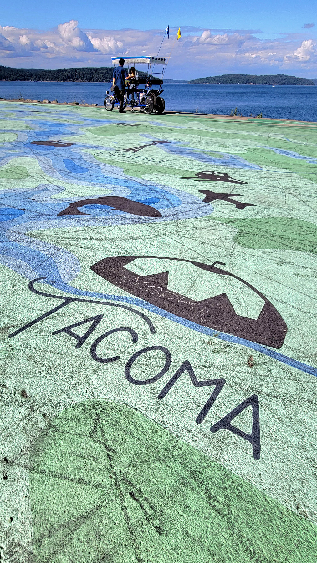The waterfront promenade at Point Ruston is accentuated by an artistic orca-embedded map of Tacoma, Washington, and Puget Sound.