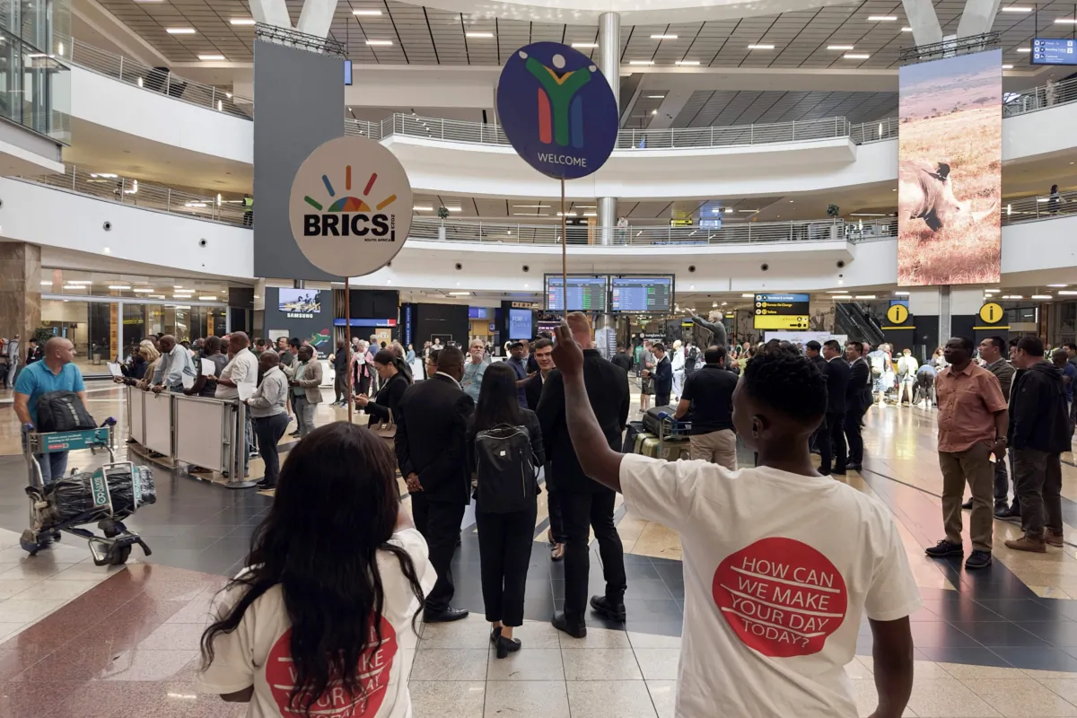 BRICS volunteers hold signs at the international arrivals terminal at the OR Tambo International Airport in Ekurhuleni, South Africa, on Aug. 21, 2023. (Marco Longari/AFP via Getty Images)