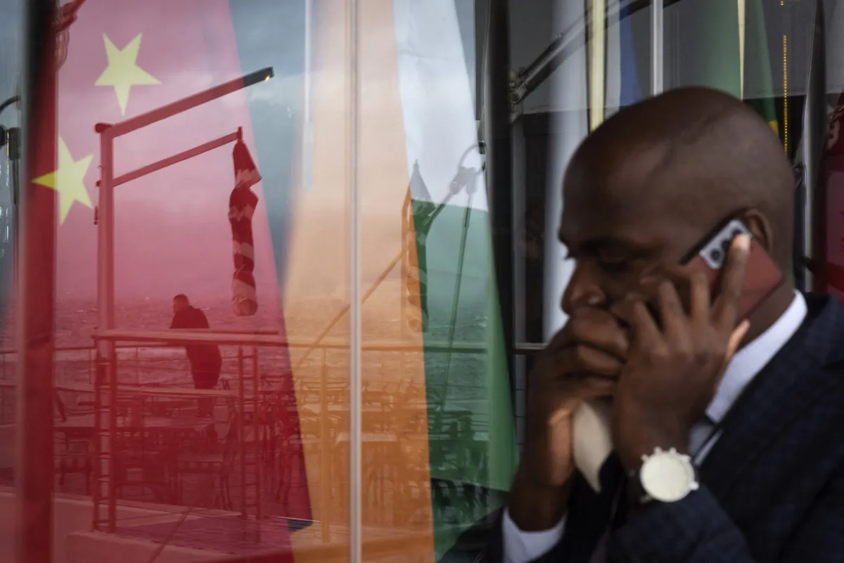 A man talks on a mobile phone as he walks past a view of a reflection on a window of another man staring at the sea in front of the national flags of the on the the BRICS (China, India, Russia, South Africa, Brazil) countries during the BRICS Foreign Ministers Meeting in Cape Town, on June 02, 2023. Foreign ministers from BRICS -- a five-nations bloc including Brazil, Russia, India, China and South Africa -- were meeting in Cape Town on Thursday and Friday. The talks came ahead of a heads of state summit in August, which is proving problematic for the host, South Africa, due to the possible attendance of Russian President Vladimir Putin, who is the target of an International Criminal Court (ICC) arrest warrant, stemming from Russia's invasion of Ukraine. (Photo by RODGER BOSCH / AFP) (Photo by RODGER BOSCH/AFP via Getty Images)