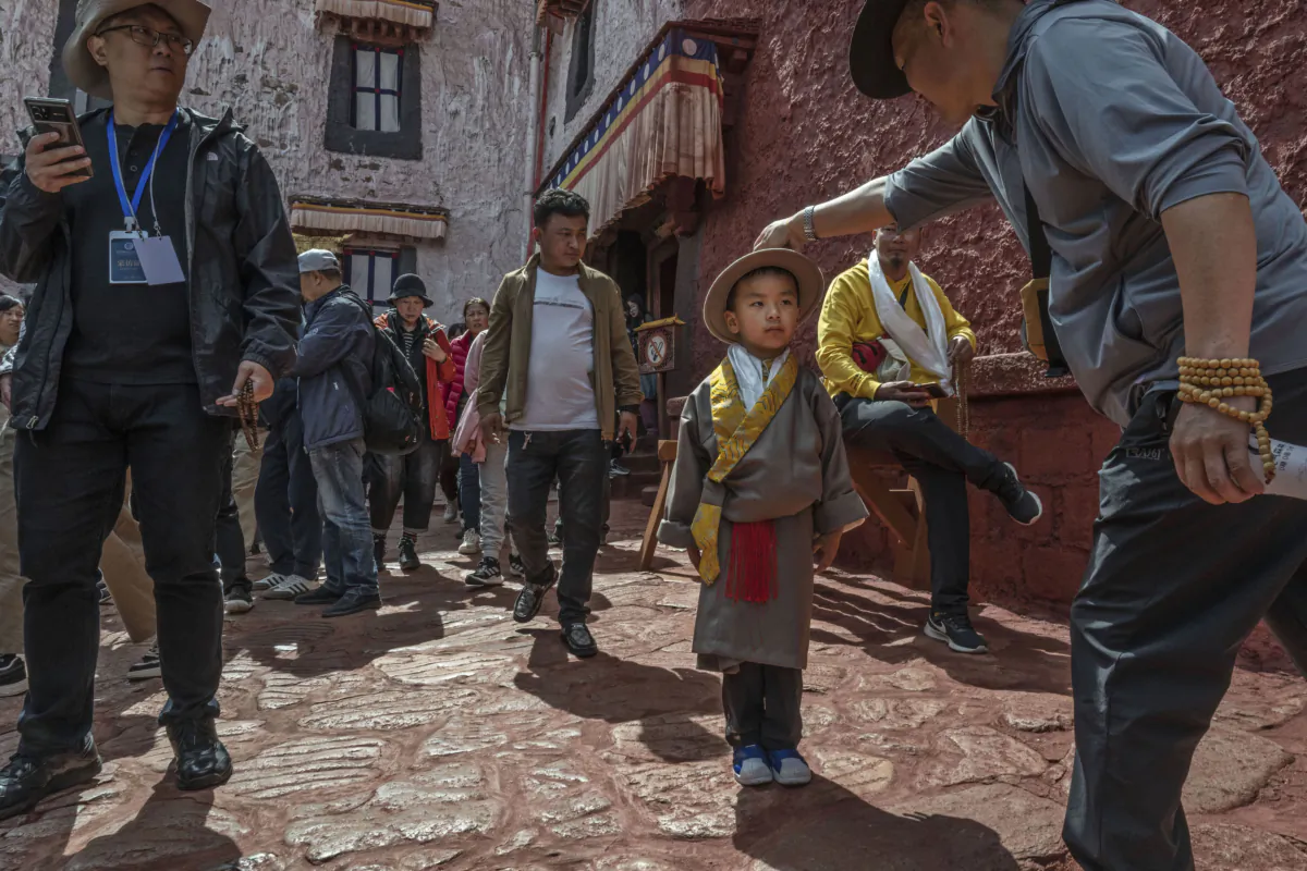 A Tibetan Buddhist man adjusts the hat of a young boy in traditional clothing while visiting the Potala Palace, a UNESCO World Heritage site, during a government organized visit in Lhasa, Tibet, China, on June 16, 2023. (Kevin Frayer/Getty Images)
