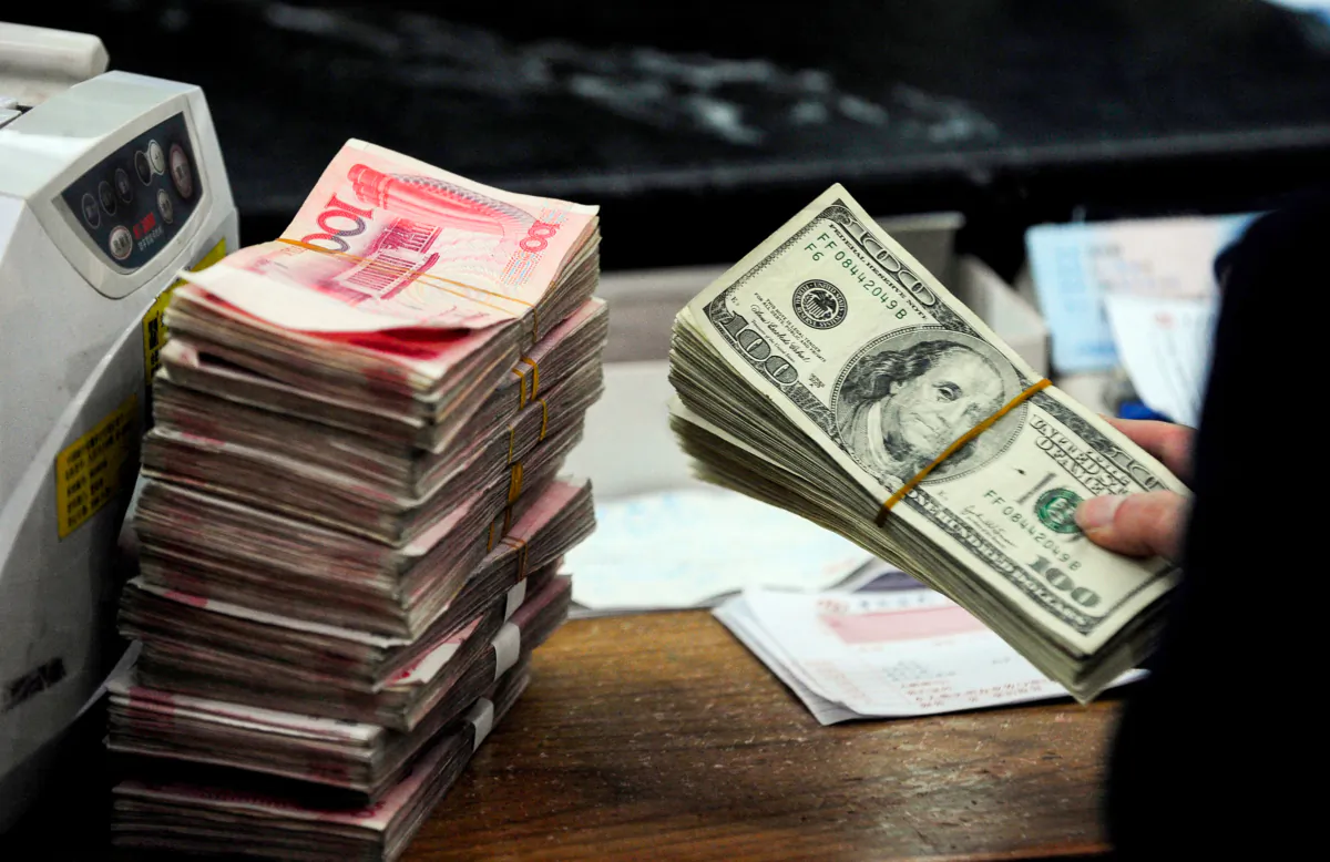A Chinese bank worker prepares to count U.S. dollar bills and a stack of 100 yuan notes at a bank in Hefei, Anhui Province, China, on March 9, 2010. (STR/AFP via Getty Images)