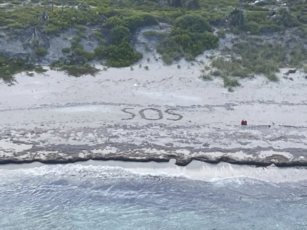 The letters SOS etched in the sand during the Coast Guard's rescue on Aug. 18, 2023, of a 64-year-old man who spent three days stranded on an island in the Bahamas until being rescued. (U.S. Coast Guard via AP)