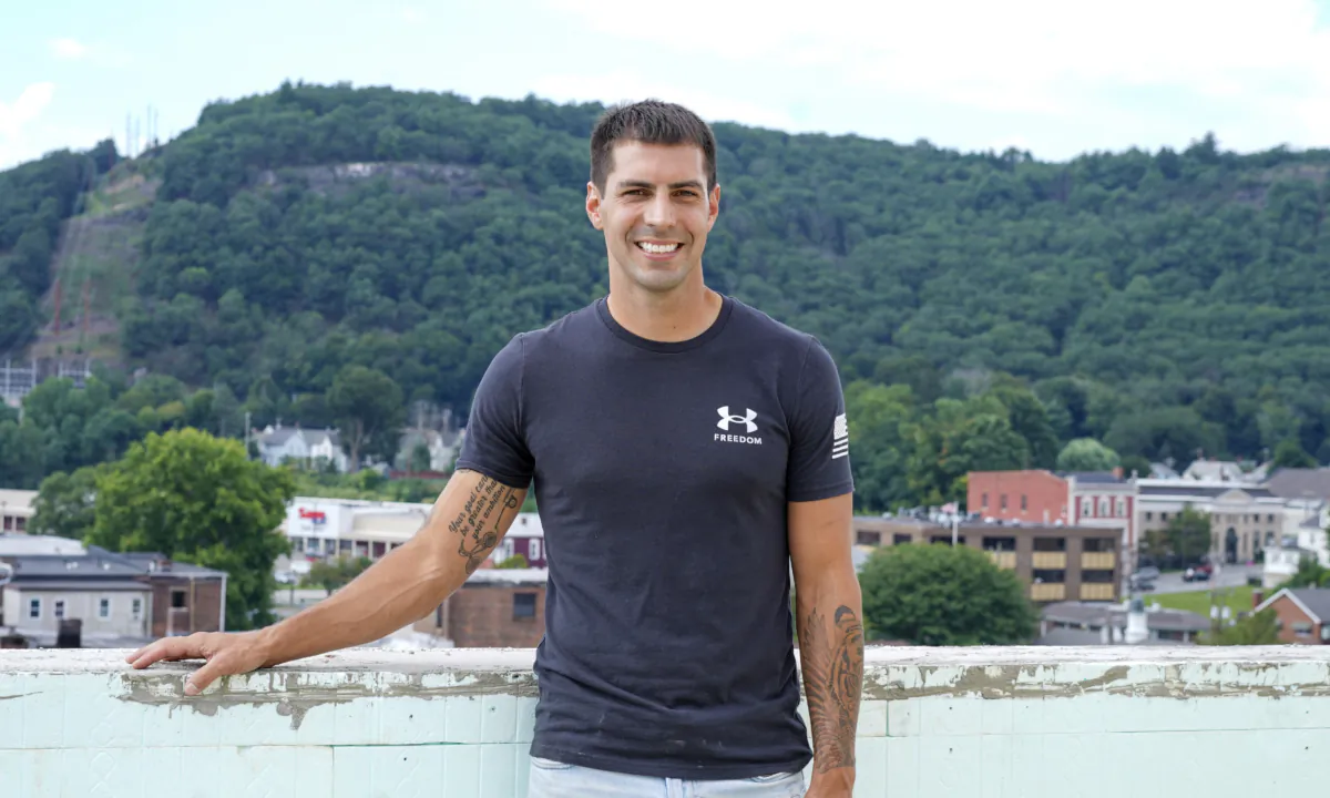 Cory Puopolo stands on the unfinished roof top of the future Front Hotel in downtown Port Jervis, N.Y., on Aug. 17, 2023. (Cara Ding/The Epoch Times)